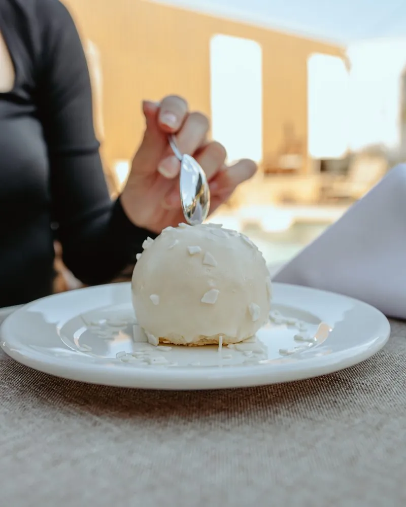 Beli desert u obliku kugle, na tanjiru uz kašičicu