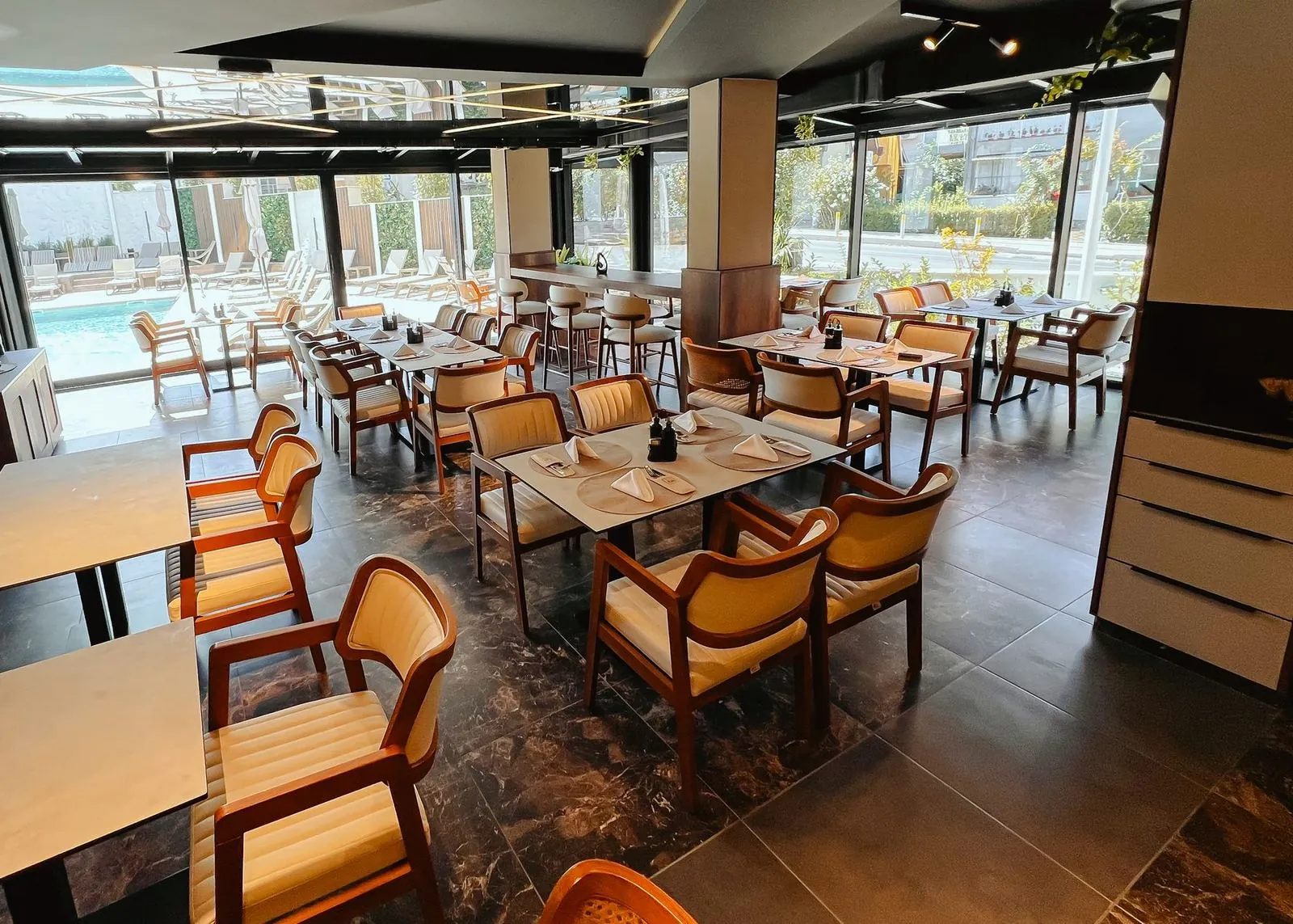 Enterijer restorana Žar&So, sa staklenim zidom prema bazenu